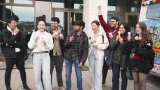 8 students outside the Nucleus Building laughing and eating icecream