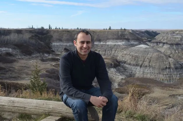 Professor Steve Brusatte sitting above a canyon