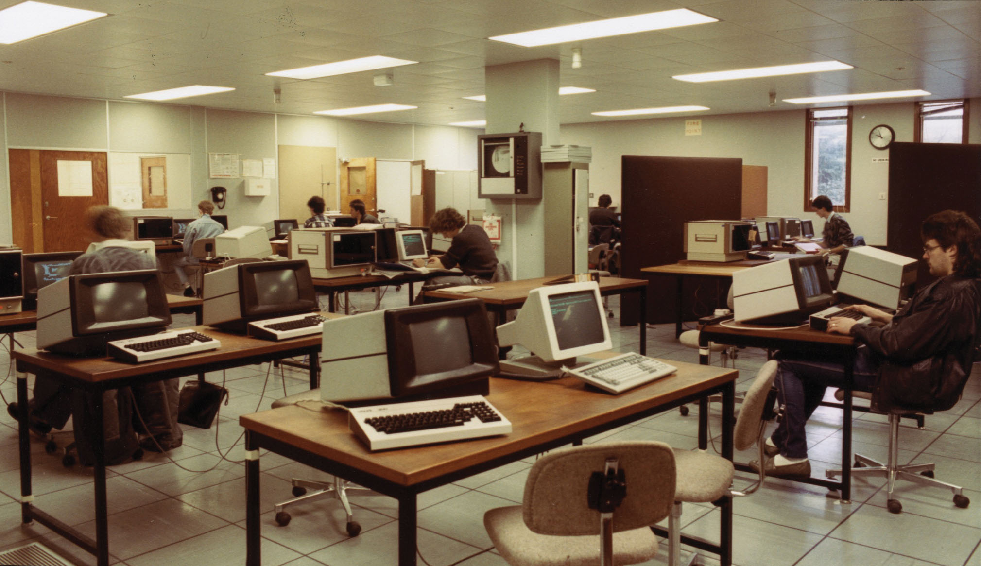 Office full of computers and workers from 1970s or 1980s.